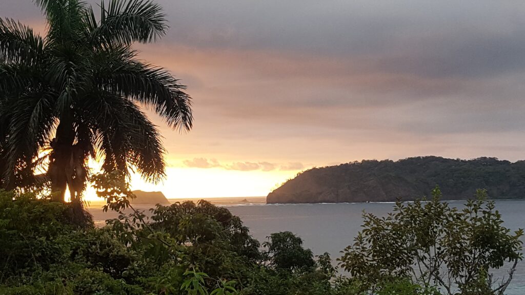 Warm travel destination Costa Rica. Sunrise over water, hills, and trees. 
